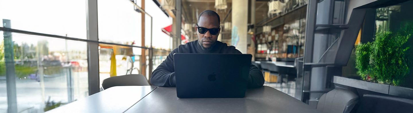 A man wearing a black sweatshirt and glasses in front of a computer